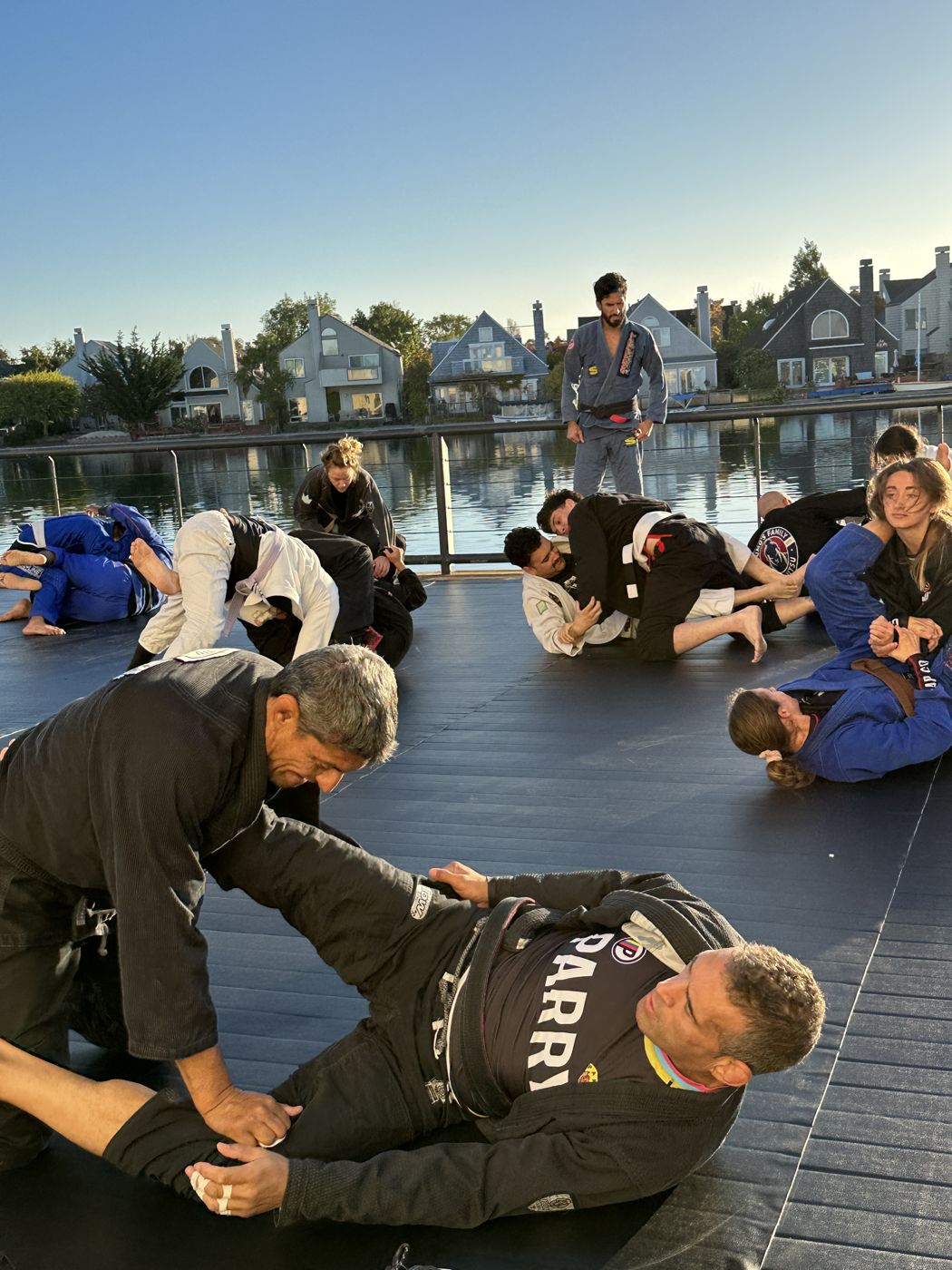 Black belts drilling a guard pass by the water